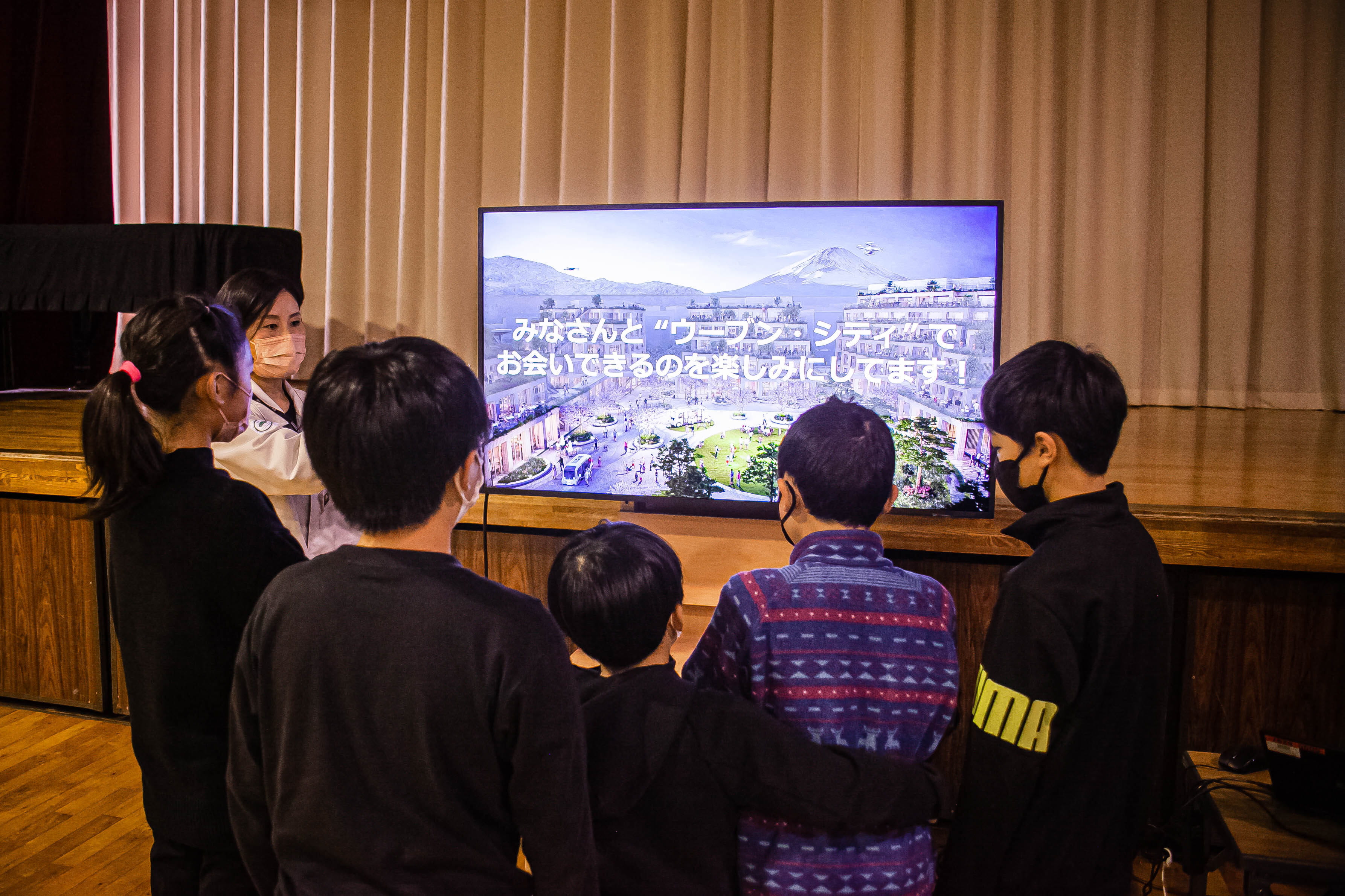 Photo of students gathered to watch a video introducing Woven City