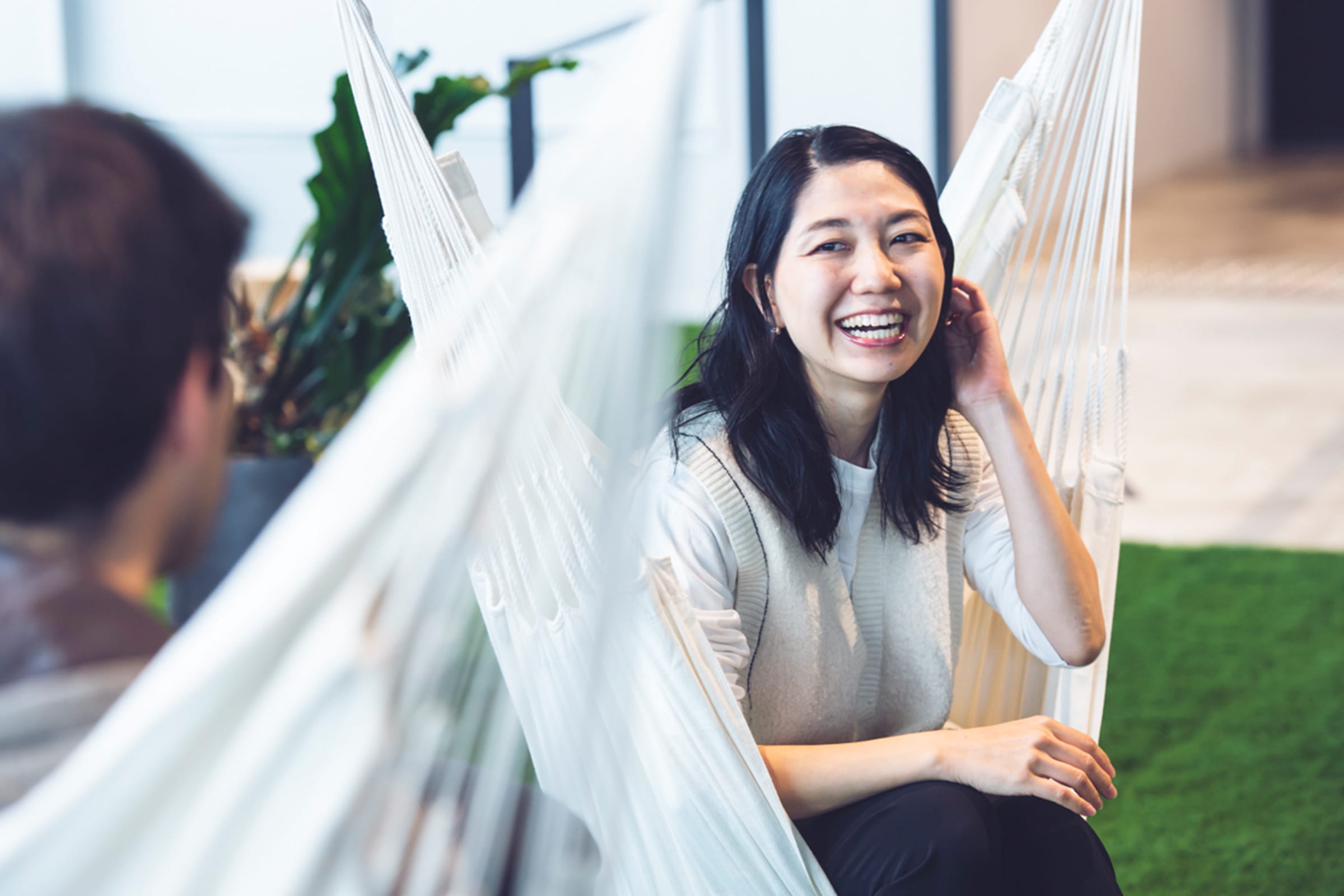 Photo of Tani talking to Pelaez while sitting on hammocks at the office