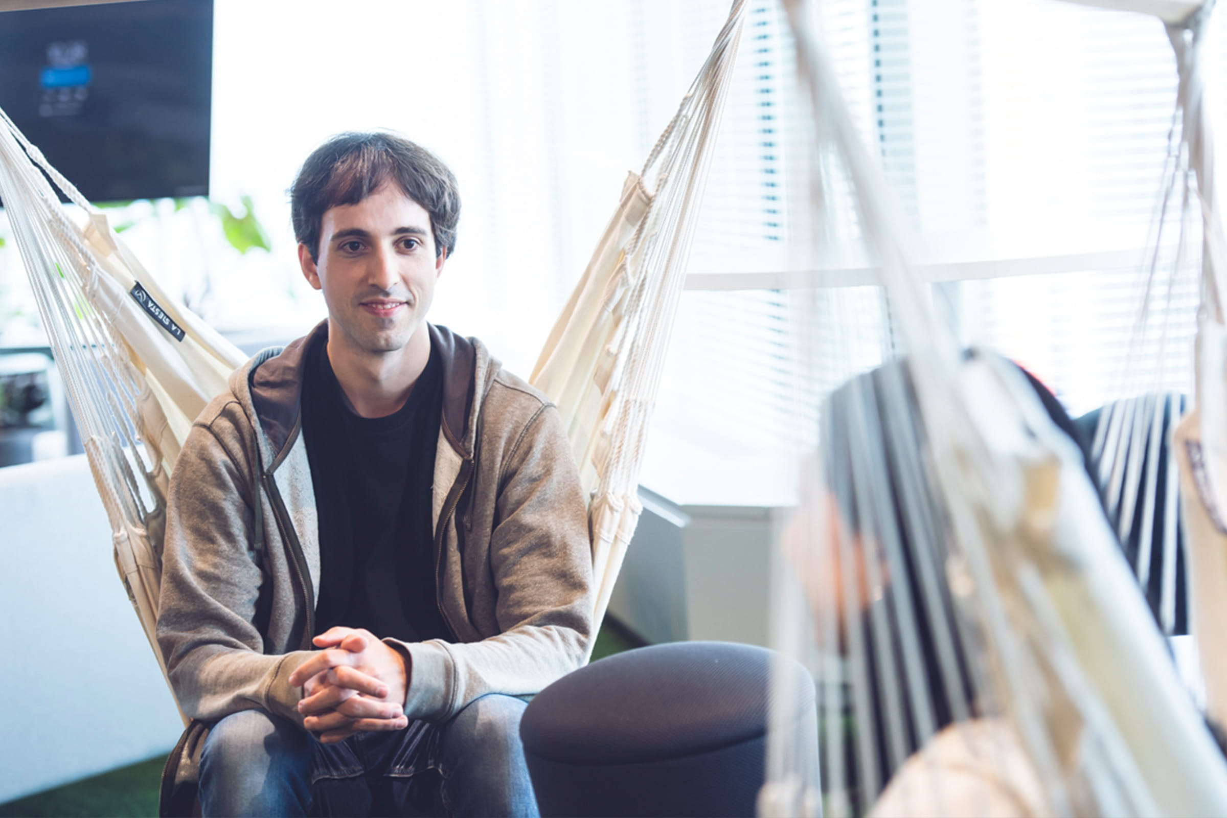 Photo of Pelaez talking to Tani while sitting on hammocks at the office