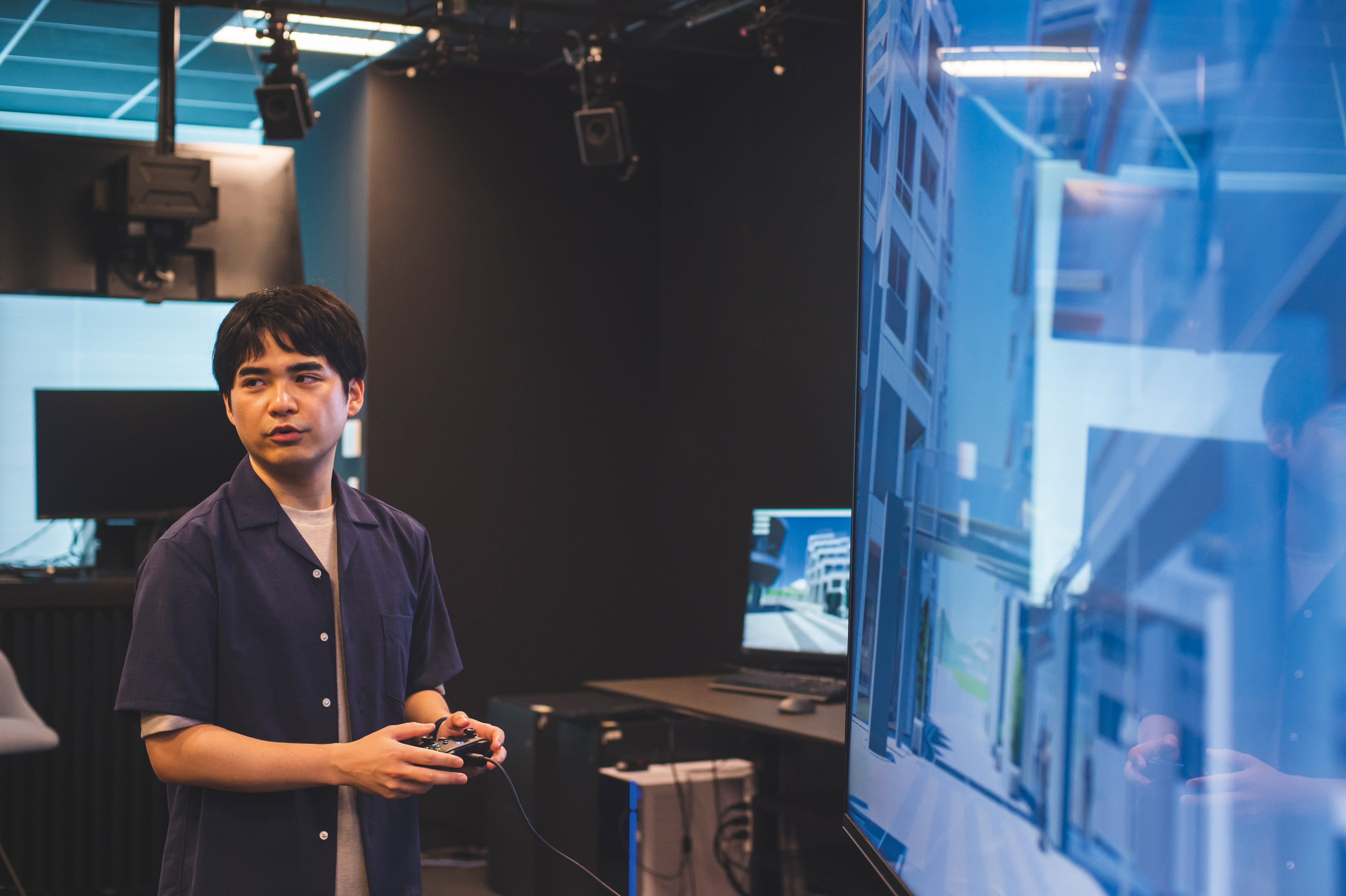 Photo of Kojima from Woven by Toyota standing by a monitor, controlling the Woven City digital twin