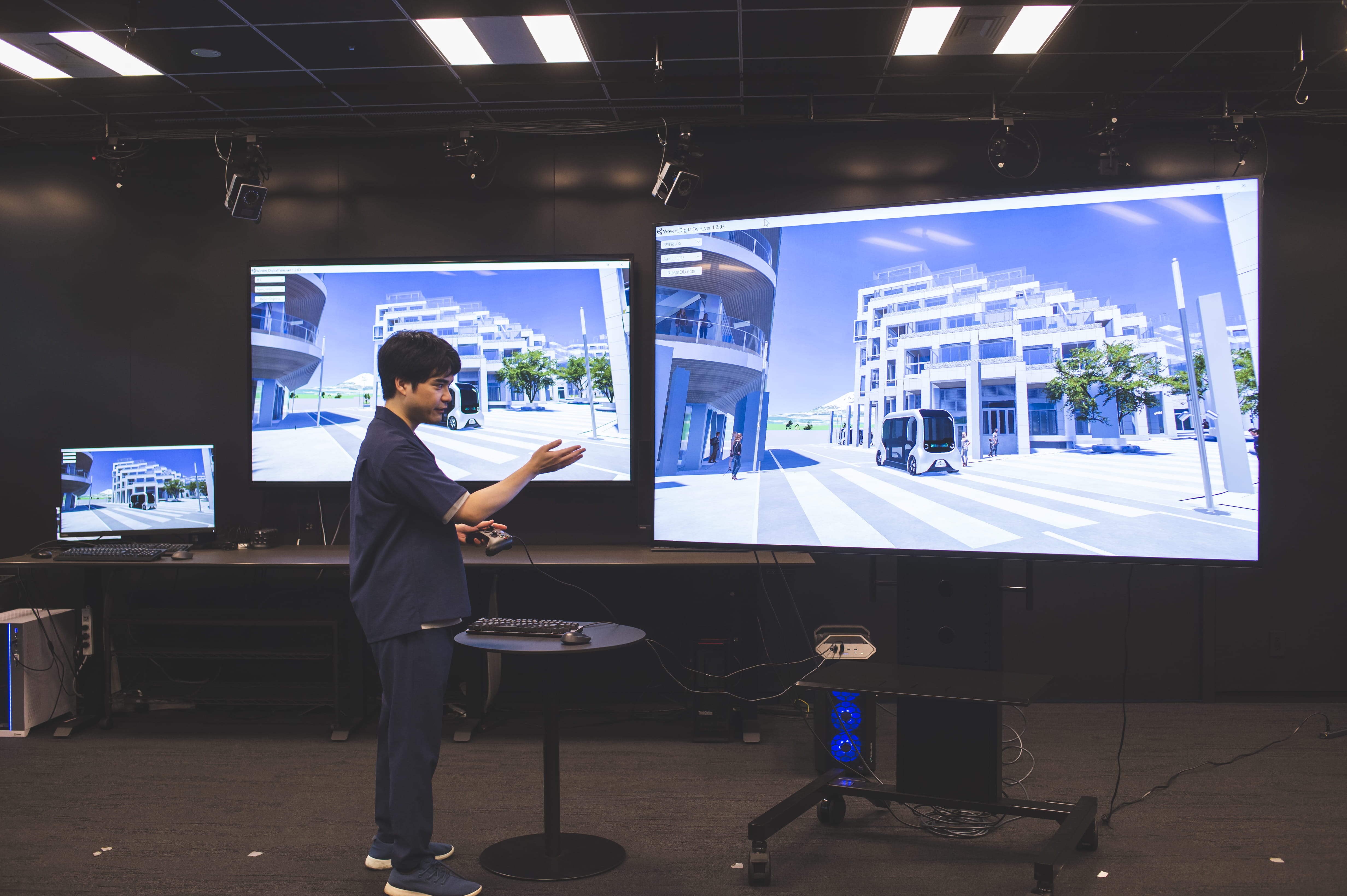 Photo of Kojima from Woven by Toyota speaking in front of screens that show the digital twin of Woven City